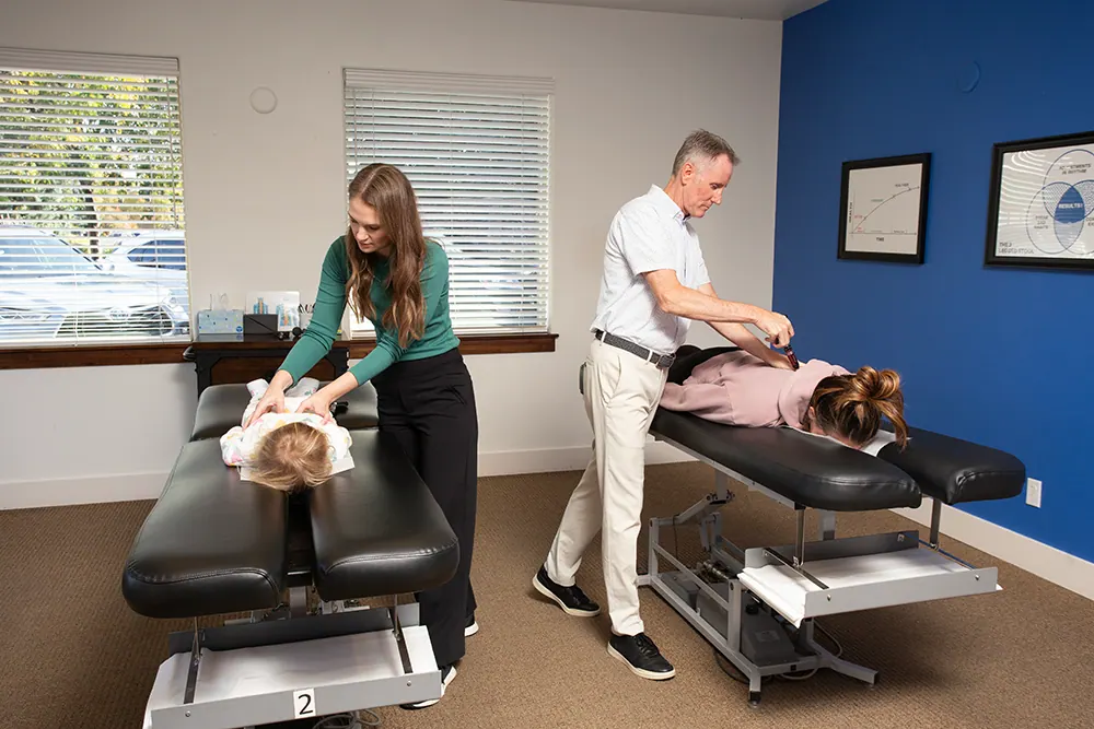 Both chiropractors adjusting patients in the treatment room