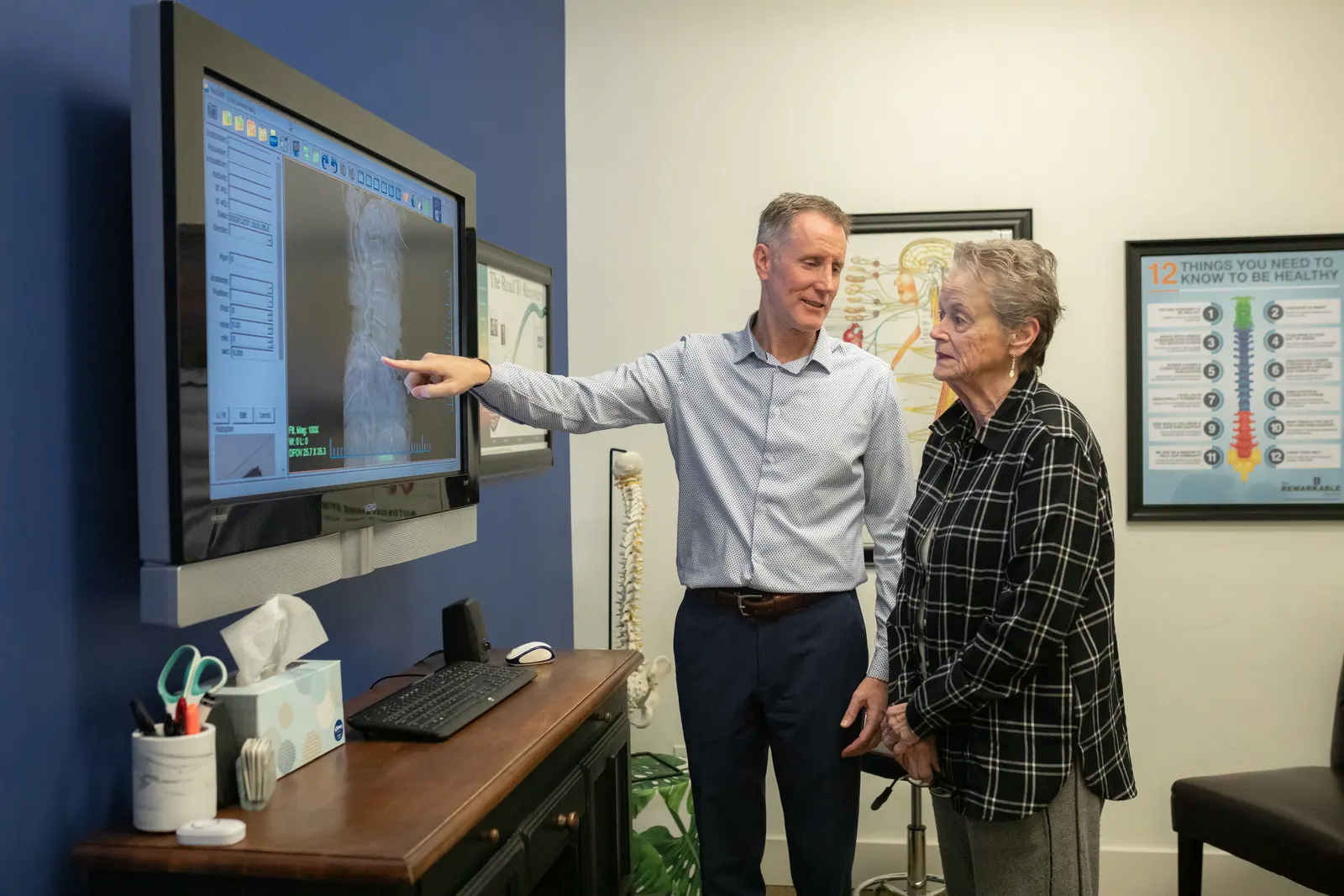Dr. Craig Ellison reviewing spinal scan results with a patient on a screen