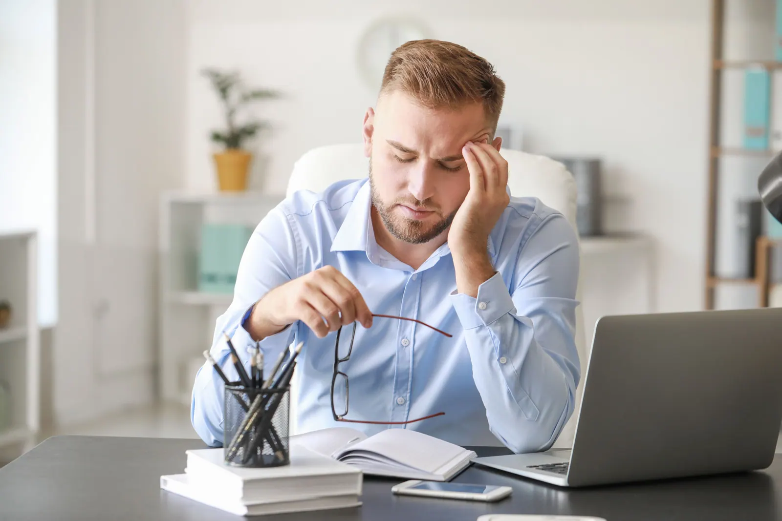 Young man suffering from headache in office